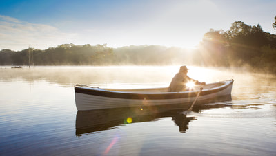 Photo of Man in row boat on foggy lake