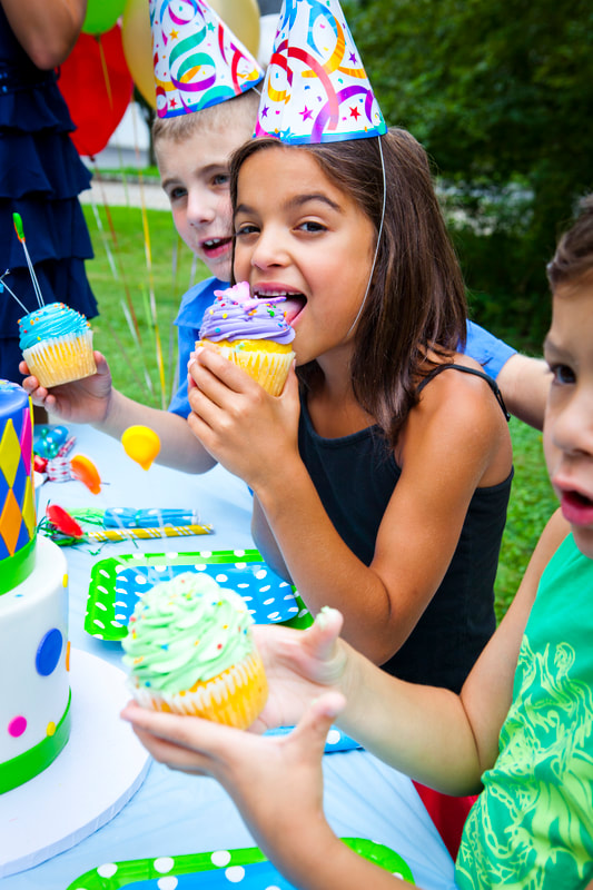 Photograph of kids at a birthday party eating cupcakes