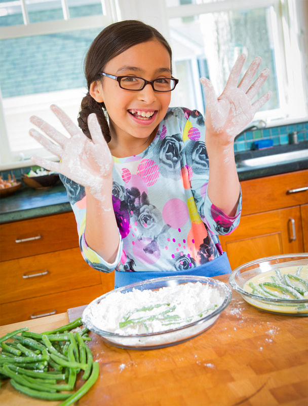 Photograph of a girl cooking in kitchen with hands full of flour