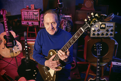 Photo of Les Paul holding a Serial #001 guitar in his home recording studio in Mahwah New Jersey
