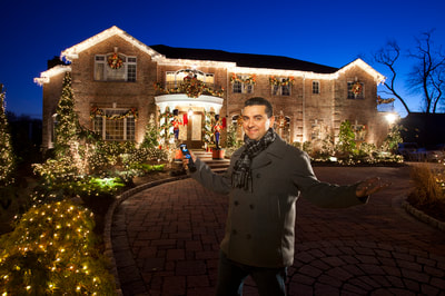 Photo of Buddy the Cake Boss holding an Elan Remote control in front of his home with Christmas lights