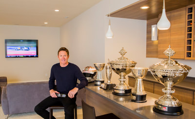 Photo of IndyCar Racer Scott Dixon with his trophies in his basement for Elan