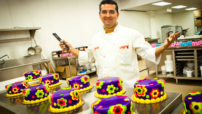 Photo of Buddy the Cake Boss holding an Elan Remote control in front of cakes at his production facility