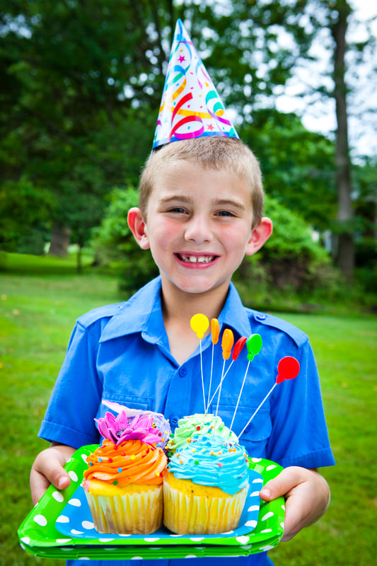 Photograph of Boy at a birthday party with cupcakes