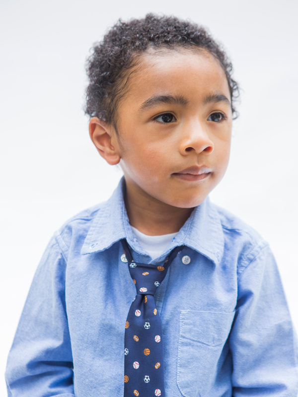 Photograph of a black baby boy wearing a tie on white seamless background