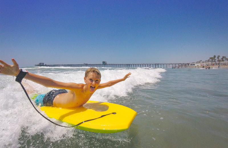 Photograph of a caucasian teenage boy body surfing on yellow boogey board