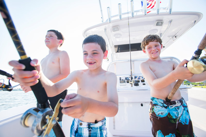 Photograph of Boys in swimsuits fishing off back of a boat