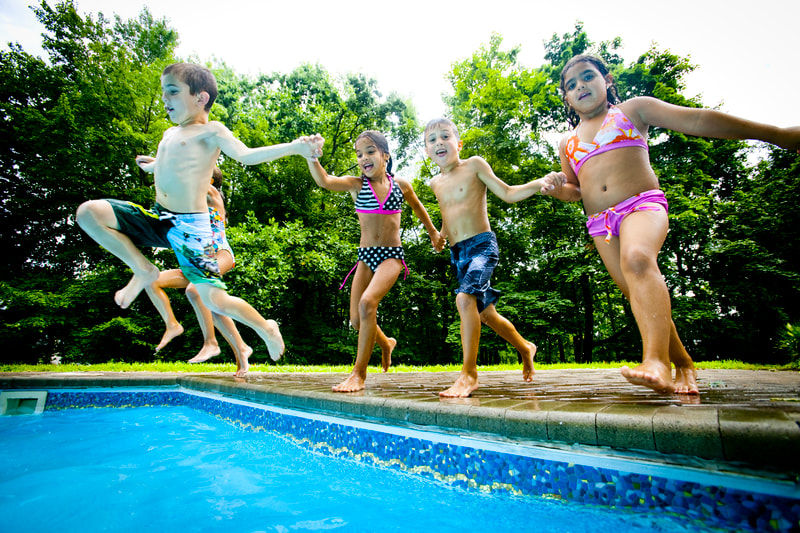 Photograph of kids in swimsuits jumping in swimming pool together