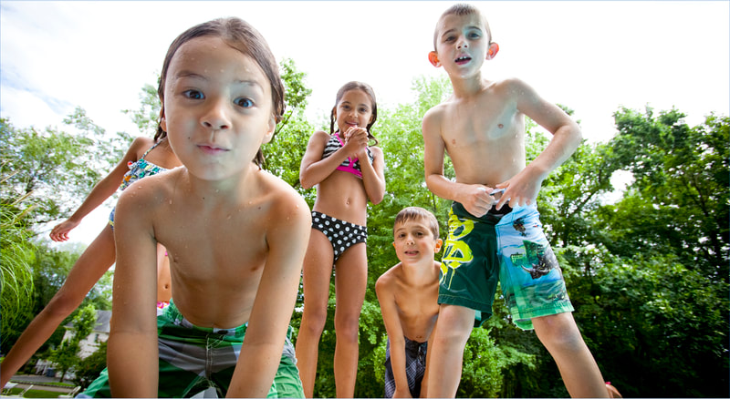 Photograph of kids in swimsuits posing for camera at swimming pool 